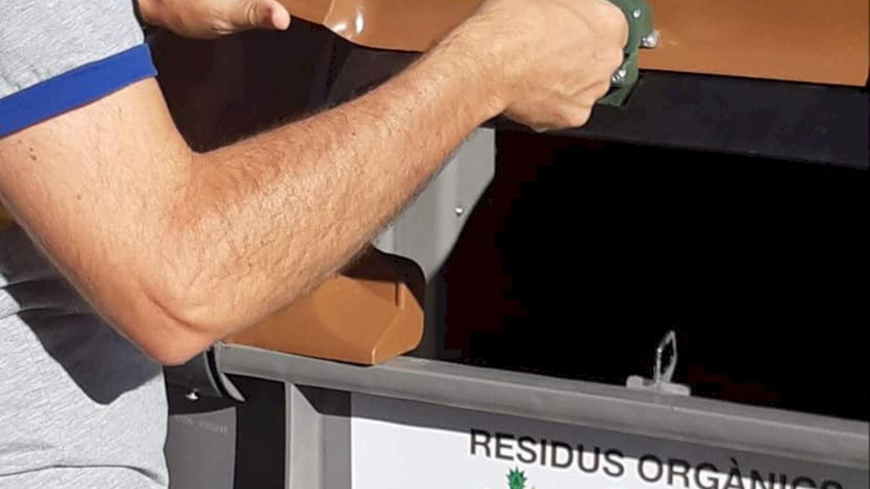 Persona abriendo el contenedor marrón