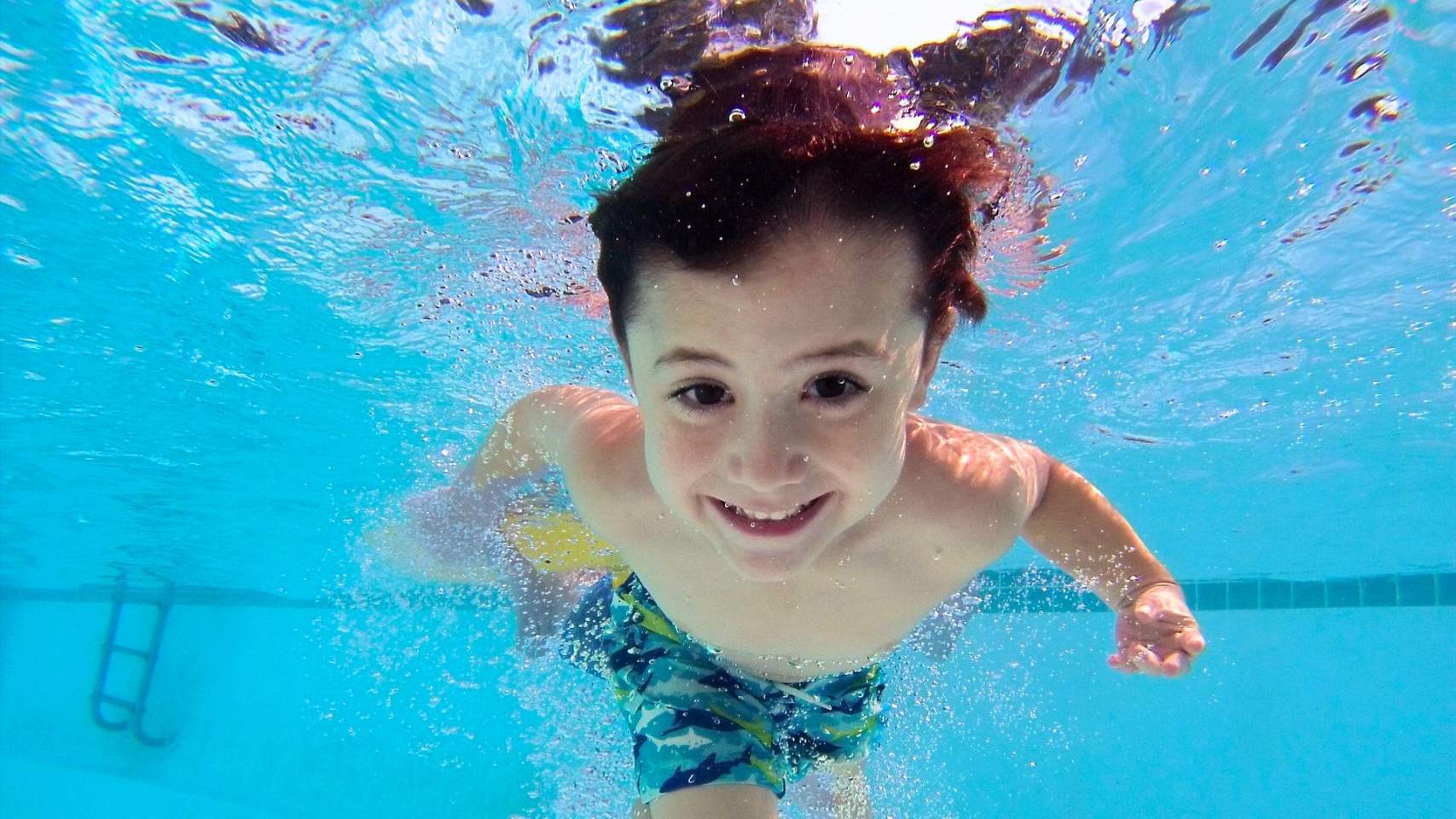 Un xiquet nada en una piscina