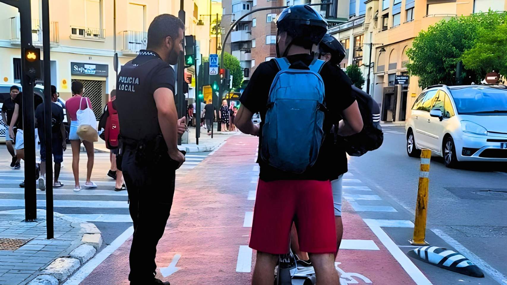 Un policia local informa uns joves en l'estiu de 2024